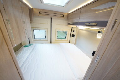 Grand couchage surmonté en pied de lit de placards supplémentaires.