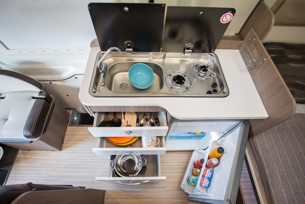 Cuisine équipée d'un réfrigérateur 90L, d'un évier, d'un réchaud deux feux et d'un plan de travail escamotable.