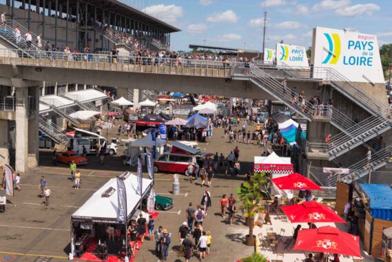 Le paddock du circuit du Mans envahi par une foule colorée de modèles anciens et de visiteurs curieux