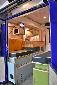 Les parois extensibles du PlugVan libérent un couloir central bordé de deux rangées d'équipements et de mobilier en bois