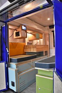 Les parois extensibles du PlugVan libérent un couloir central bordé de deux rangées d'équipements et de mobilier en bois