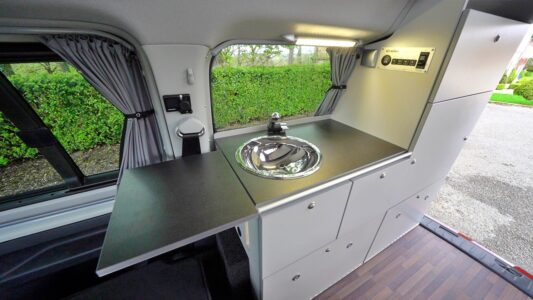 Le meuble latéral regroupe la cuisine et les rangements. Réchaud et glacière sont dans des tiroirs coulissants.