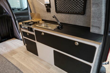 Une cuisine petit format mais fonctionnelle, avec réchaud, évier, rangement et extension latérale.