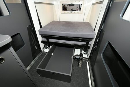 Une partie du lit peut être basculée sur l'autre pour accéder au grand tiroir de rangement. On aperçoit à droite le vérin électrique.