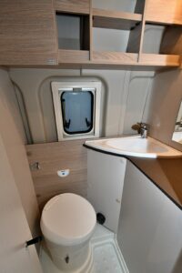 Le cabinet de toilette accueille un WC, de nombreux rangement, une baie latérale, un lavabo d'angle. La douche est isolée par un rideau souple