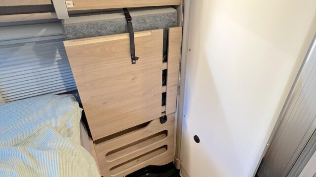 Le sommier et son matelas, relevés et fixés contre la paroi. La cloison pivotante du cabinet de toilette viendra les protéger des éclaboussures.