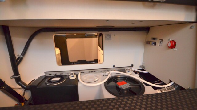 Outre sa fonction d'extension du couchage de banquette, le retour en L du bloc cuisine sert de rangement pour le matériel de couchage (draps, oreillers…) et de logement technique (réserves d’eau, tableau de fusible, vanne de gaz).