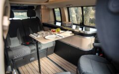 Signé Westfalia, l’aménagement demeure conventionnel, avec un bloc cuisine latéral prolongé d’un meuble de rangement à l’arrière. Coulissante sur rails, la banquette permet de moduler l'espace selon les besoins. ? Mercedes-Benz