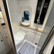 Le coin toilette dispose notamment d'un WC banquette, d'une vasque, d'un bac à douche avec deux bondes d'évacuation et d'une petite baie.