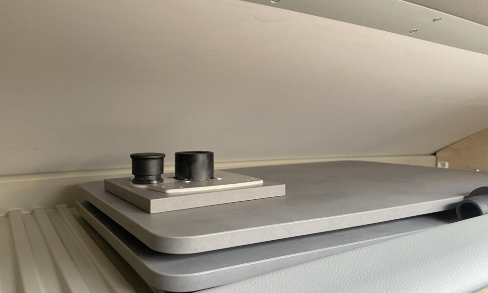 La table (84,5 x 42 cm) et son pied peuvent être rangés dans la profonde niche qui surplombe la cabine. Le rangement se ferme à l'aide d'une porte.