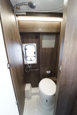 Benimar B161ES. L'espace dévolu au bac à douche est réduit à la portion congrue. En position relevée, le lavabo disparait dans le panneau à droite de la baie.