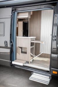 MegaLounge 640 - Libéré du frigo, le bloc cuisine compte de nombreux rangements (dont un accessible depuis l’extérieur). On aime aussi l’idée de la tablette escamotable, qui coulisse vers l’extérieur lorsque la porte latérale est ouverte. Crédit ? MegaMobil