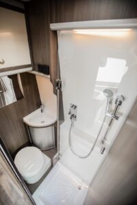 MegaLounge 640 - La cabine de douche se forme ici à l’aide d’une innovante paroi pivotante en acrylique (concept breveté), qui vient protéger la partie WC/meuble de lavabo des projections d’eau. Crédit ? MegaMobil