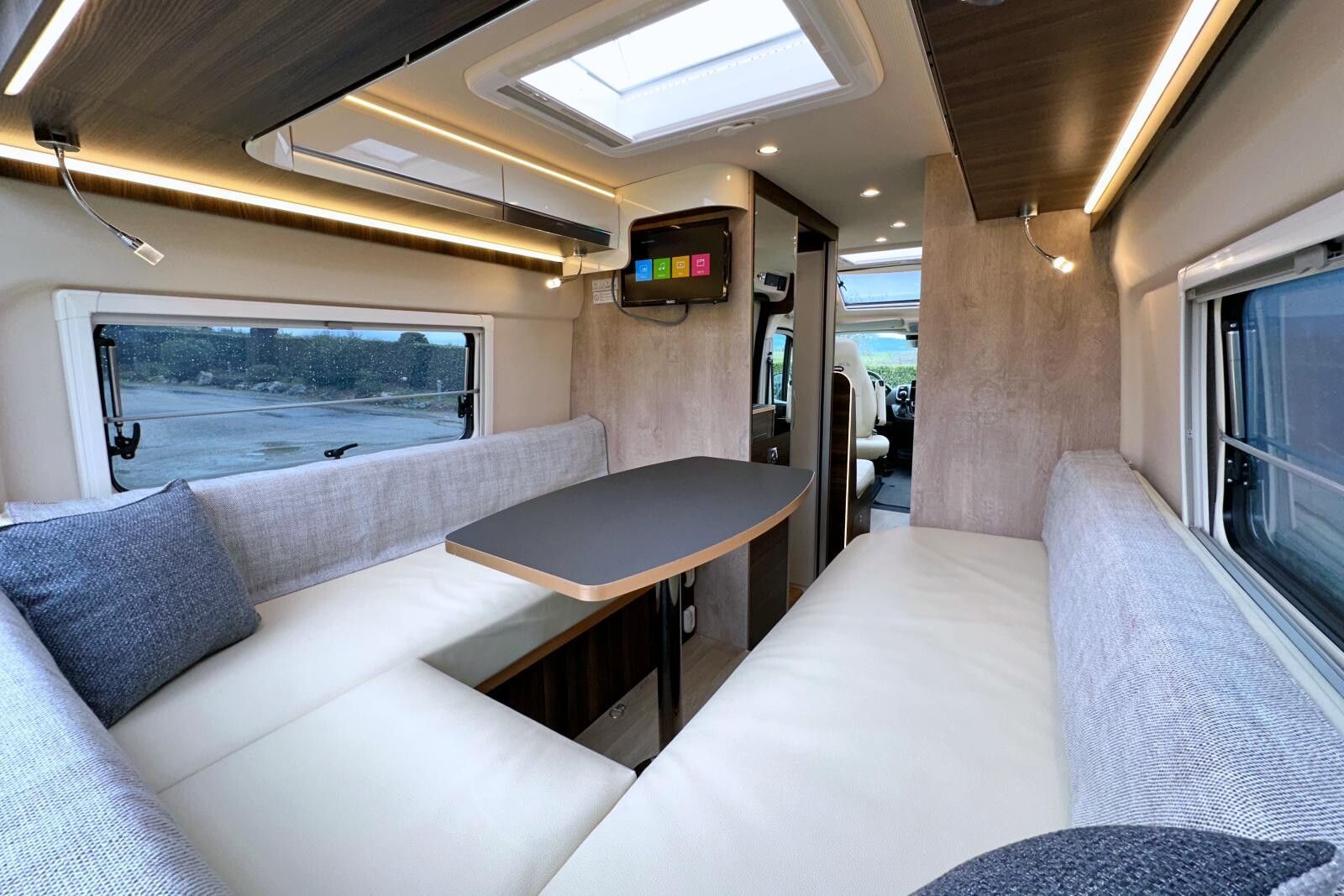 Le salon en U bénéficie de nombreux rangements et éclairages circulaires.