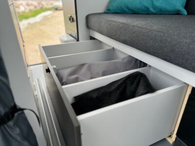 Sous la banquette fixe, un grand tiroir compartimenté de 145 litres, non pas monté sur coulisses, mais sur des roulettes