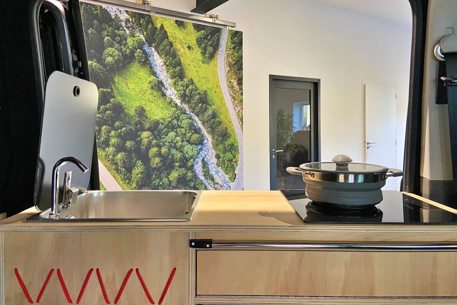 Esprit vanlife avec l'association de la finition bois de peuplier verni et plaque de cuisson à induction en verre.
