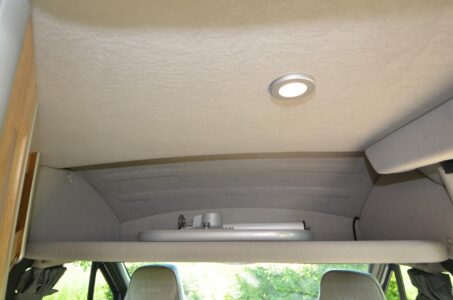 Quand ils ne sont pas utilisés, le plateau de table et son pied viennent se loger dans une très astucieuse niche escamotable sous le pavillon en cabine. La tablette se rabat et se verrouille contre le plafond pour augmenter la hauteur en cabine.