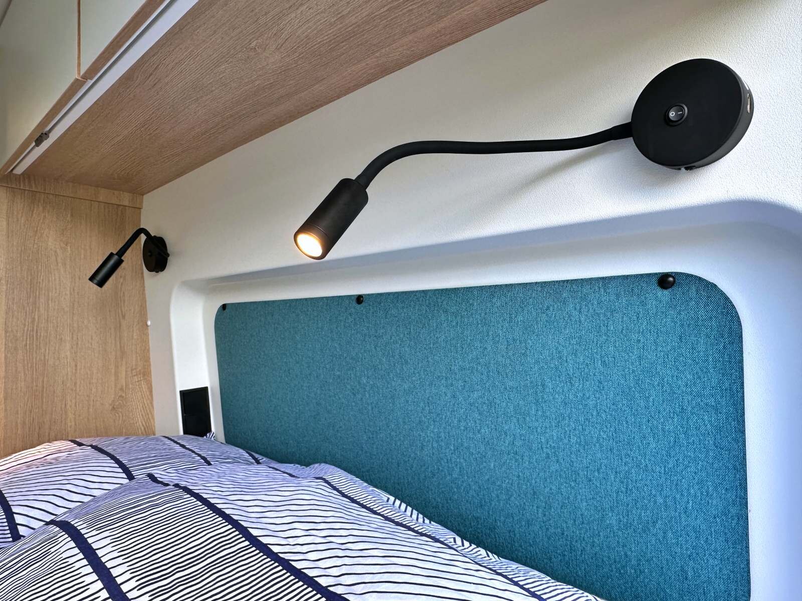 La tête de lit offre un confort supplémentaire et 2 liseuses indépendantes au-dessus de chaque zone de couchage. 4 placards de pavillon et 2 prises USB complètent l’équipement de la chambre.