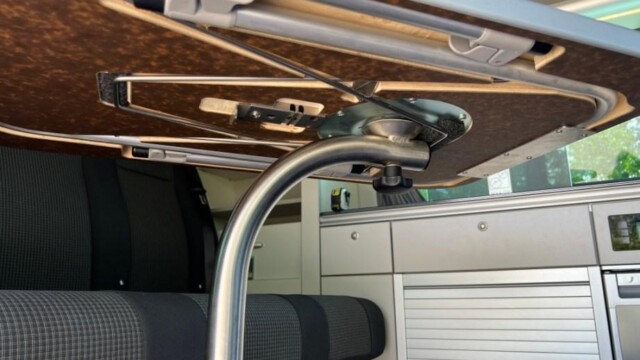 Dans l'épaisseur du plateau de table, quatre pieds télescopiques. Ce dispositif exige en conséquence une table épaisse et assez lourde à manipuler.