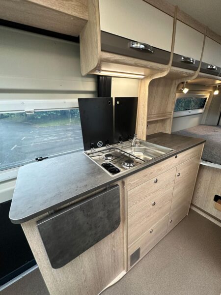 Un grand plan de travail de chaque côté du combiné réchaud/évier et une tabelle rabattable : il est confortable de cuisiner à bord du Summit 600 B Plus. cuisine fourgon Pössl Summit 600 B Plus