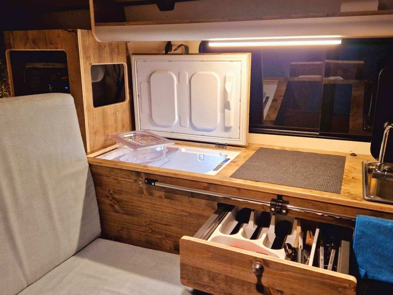 Le détail du plan de travail de la kitchenette avec glacière, tiroir et évier.