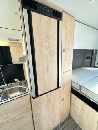 CleverVans Celebration 600. Frigo 90 l placé en hauteur pour un meilleur accès et placard en partie basse. Frigidaire fourgon CleverVans Celebration 600