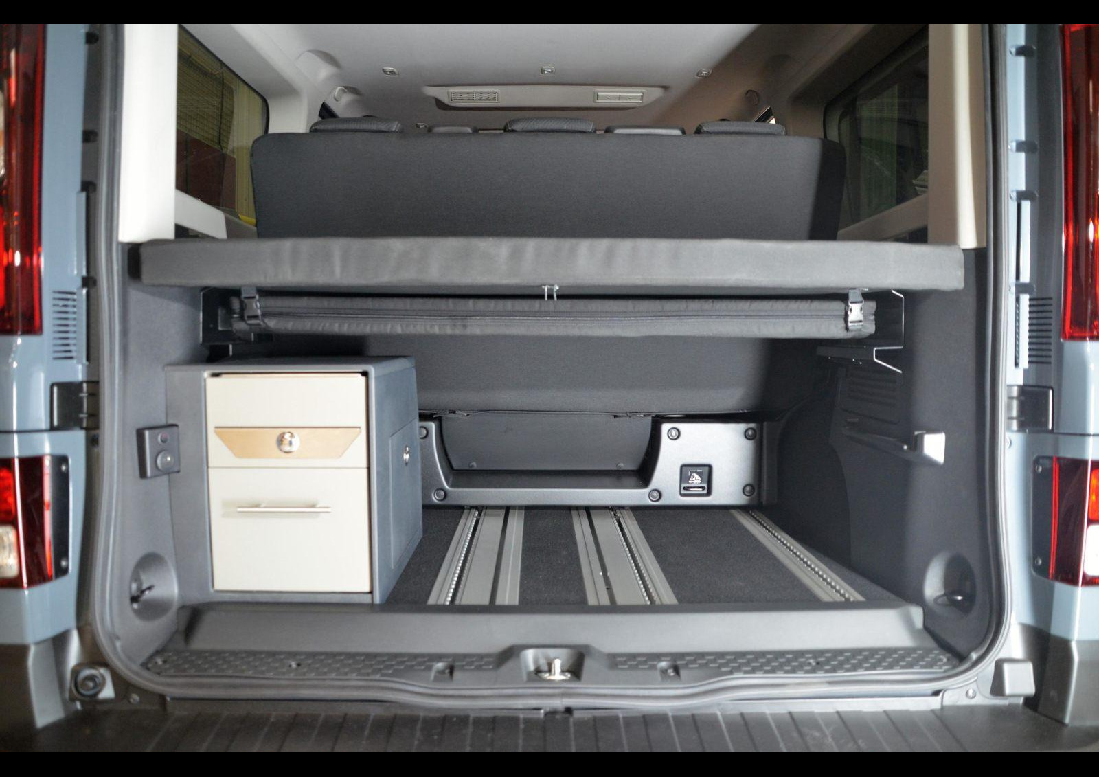 La banquette-lit pour 3 places route et 2 couchages est coulissante sur rails. Le module cuisine occupe la partie gauche de la soute. Photo © Renault renault trafic escapade